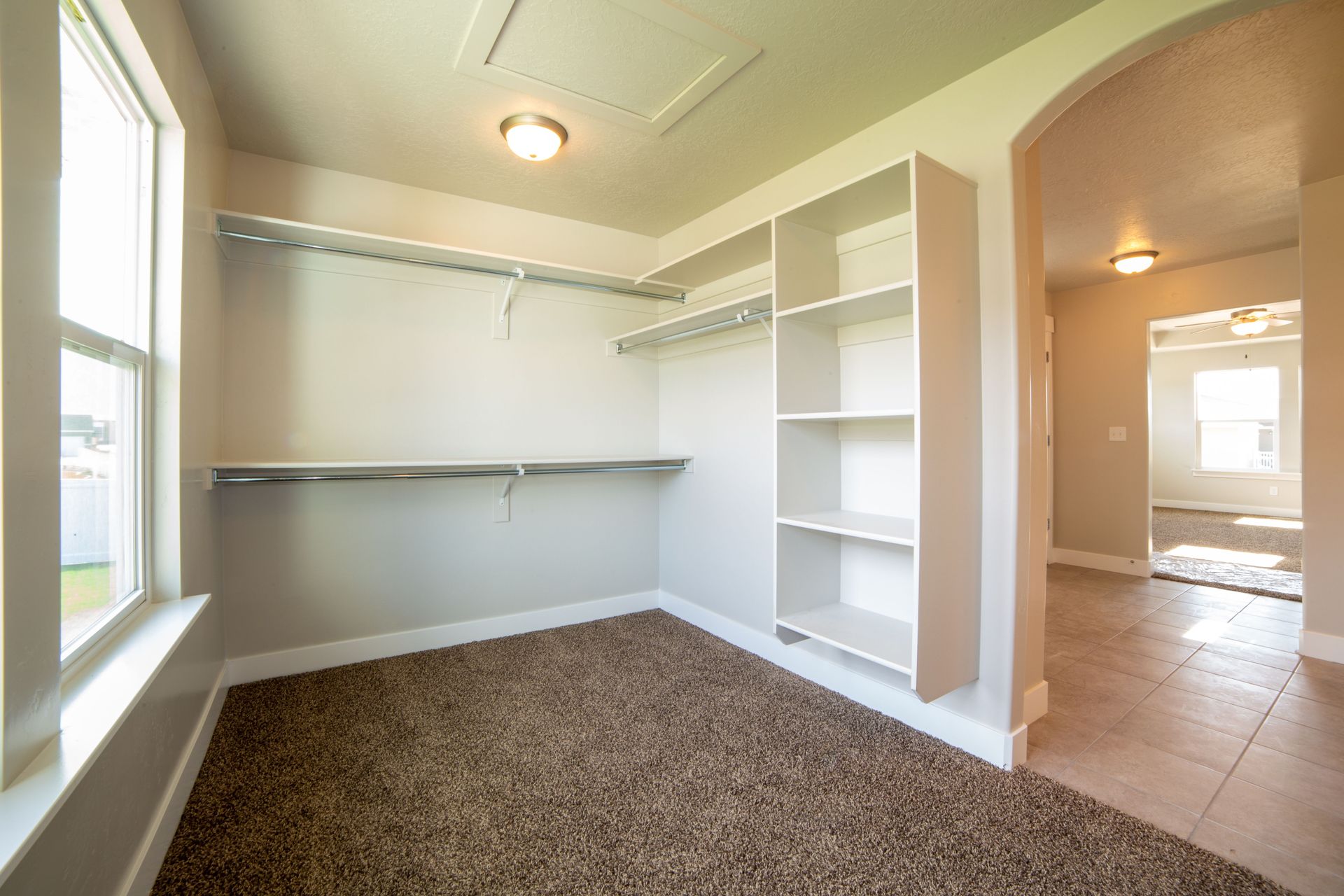 Bright and spacious modern closet with white walls and carpet flooring.